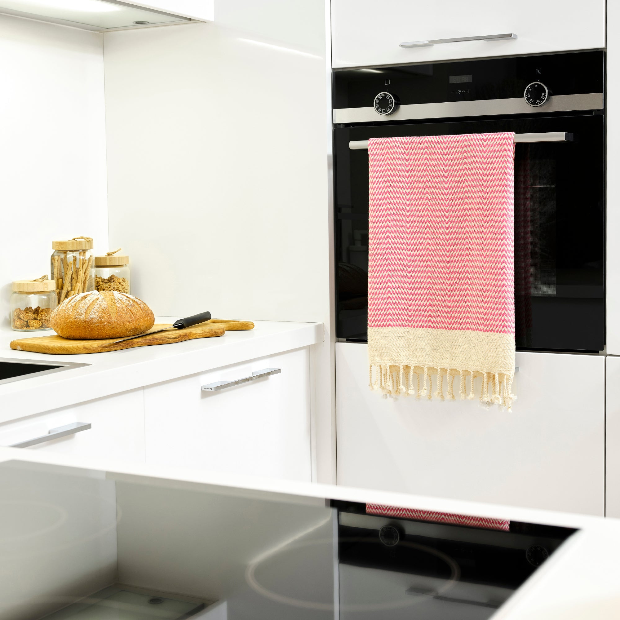 Kitchen with white cabinets, black oven, and a pink and beige towel hanging on the handle.
