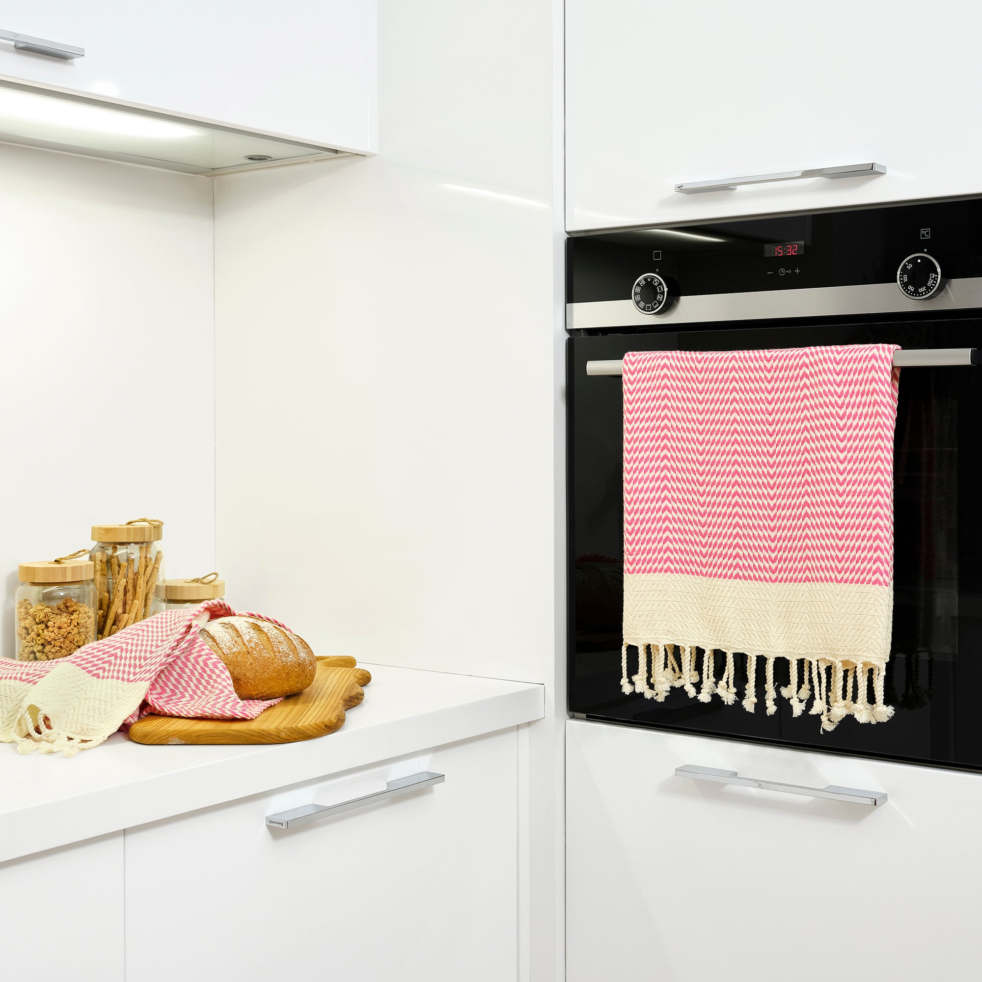 Kitchen scene with a black oven and pink and white checkered towels.