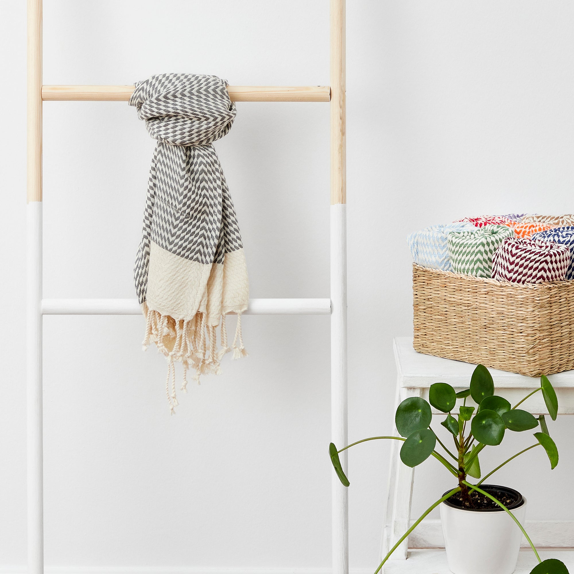 Scarf hanging on a wooden ladder with a plant and basket in the background